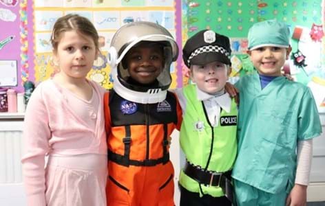 A group of four young children dressed up and smiling at the camera for 2024 Children's Mental Health Week Express Yourself day. 